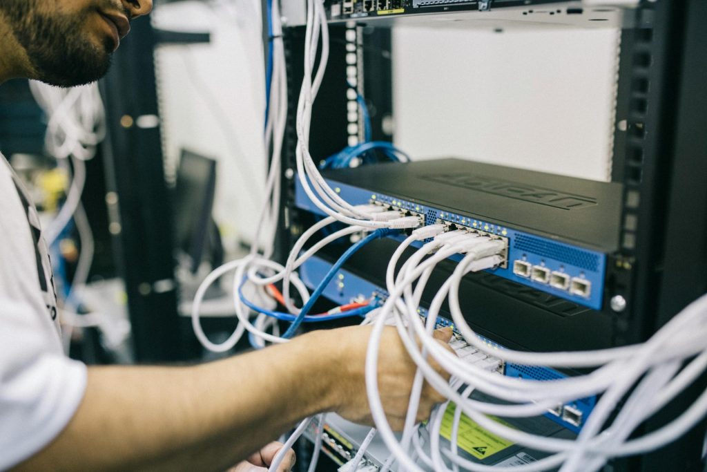 Ein IT-Fachmann konfiguriert Netzwerkkabel in einem Serverschrank, wobei der Schwerpunkt auf Ethernet-Verbindungen liegt.